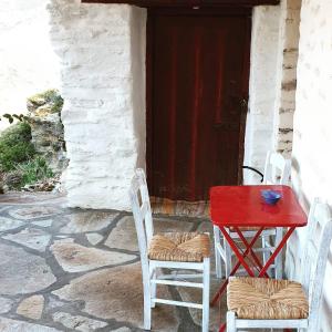 een rode tafel en twee stoelen voor een deur bij Traditional stone house 1bedroom, sea view, Syros in Ano Syros