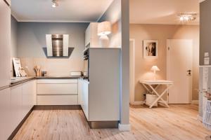 a kitchen with white cabinets and a hardwood floor at Luxus Ferienwohnung Beach Style, traumhafter Seeblick in Fulda