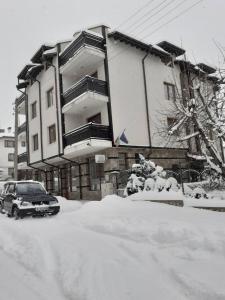 una casa con un coche aparcado en la nieve en St. Anastasia Apartments, en Bansko