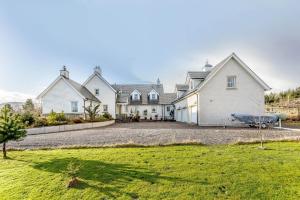 a large white house with a boat in the driveway at Glenerrick House - Loch Ness country manor - hot tub and sauna in Whitebridge