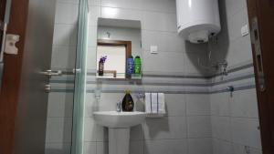 a white bathroom with a sink and a shower at Apartman Nikšić in Nikšić