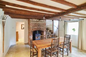 uma sala de jantar com uma mesa de madeira e uma lareira de tijolos em Rock Cottage em East Rudham