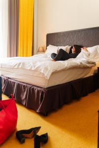 a woman laying on top of a large bed at Hotel Euler Basel in Basel