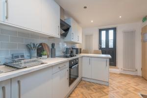cocina con armarios blancos y encimera en Heritage Serviced Suites - Serviced Apartments, en Huddersfield