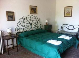 een slaapkamer met een groen bed en een tafel bij la Rocca delle Rose in Zafferana Etnea