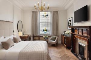a bedroom with a bed and a fireplace and a television at The Queens Gate Hotel in London