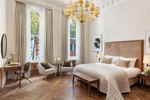 a bedroom with a large bed and a chandelier at The Queens Gate Hotel in London