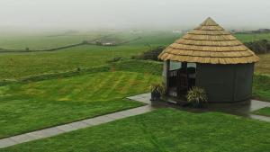 a gazebo with a straw roof in a field at Ocean View,Kinsale, Exquisite holiday homes, sleeps 22 in Kinsale