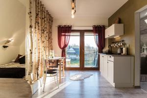 a kitchen with a bed and a table in a room at Apartamenty Magiczny Kącik in Poronin