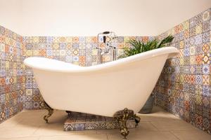 a bath tub in a bathroom with a tiled wall at Boutique Hotel Enkhuizen in Enkhuizen