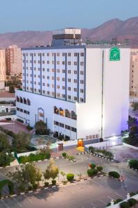 un gran edificio blanco con un letrero verde. en Hotel Muscat Holiday, en Mascate