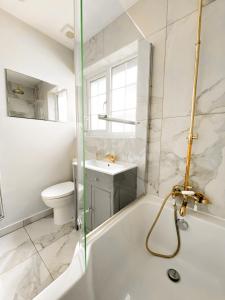 a bathroom with a tub and a toilet and a sink at Luxury & Spacious 2 Bed Annex with Private Garden in Potters Bar