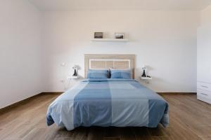 a white bedroom with a blue bed with blue pillows at Anaga Ocean Views (A): Mountain and Beach Retreat in Santa Cruz de Tenerife