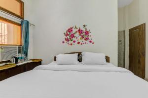 a bedroom with a large bed with white sheets and flowers on the wall at Hotel K V PALACE in Varanasi