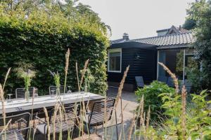 a house with a table and chairs in a garden at Vakantiehuis Duinwald, geschikt voor 8 personen in Bergen