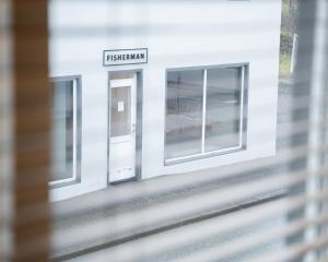 a white building with two windows and a sign that reads freshman at Fisherman Guesthouse Sudureyri in Su&eth;ureyri