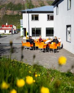 
people sitting on chairs in front of a building at Fisherman Hotel Westfjords in Suðureyri
