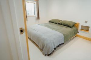 a bed in a white room with a window at Beavers Lodge. Luxury Property with Hot Tub in Tenby
