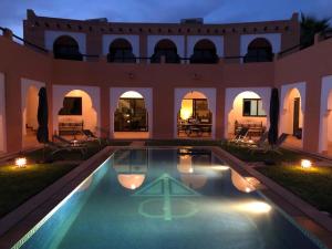 une grande maison avec une piscine la nuit dans l'établissement Riad Asmaa Agadir, à Agadir