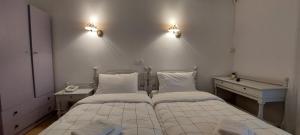 ルトラ・エディプソスにあるHotel Raniaのベッド2台 壁に照明2つが備わる客室です。