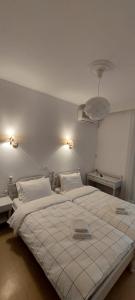 Hotel Rania في لوترا إديبسو: غرفة نوم بسرير ابيض كبير ومصباحين