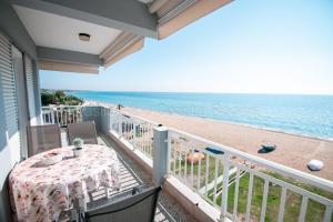 een balkon met een tafel en uitzicht op het strand bij Vasileiadou Coastal Rooms in Flogita