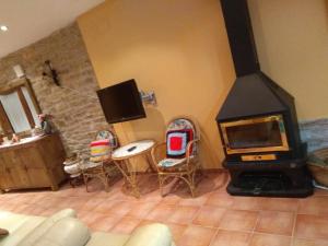 sala de estar con chimenea, sillas y TV en Casa Costeta, en Cinctorres