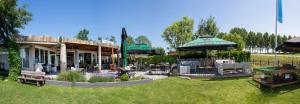 a restaurant with benches and umbrellas in a yard at Welgedacht in Sint Annaland