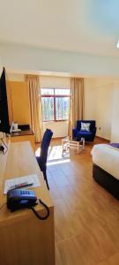 Cette chambre comprend un lit et un bureau avec un téléphone. dans l'établissement Hays Suites Hotel, à Nairobi
