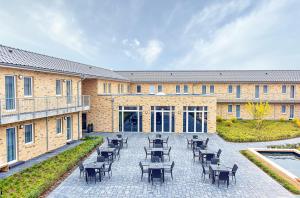 a patio with tables and chairs in front of a building at PRIMA Inn HOTEL & HOF NEURUPPIN - digitales & rezeptionsloses Motel in Neuruppin