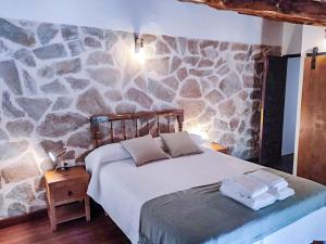 una camera da letto con un letto e una parete in pietra di Casa rural El Molino de Bogarra a Bogarra