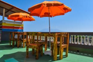 Hotel 3M Tours في Vila Nova Sintra: طاولة وكراسي مع مظلات على الفناء