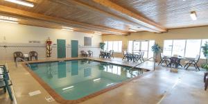 - une piscine dans un bâtiment avec des tables et des chaises dans l'établissement Holiday Inn Express & Suites Marquette, an IHG Hotel, à Marquette