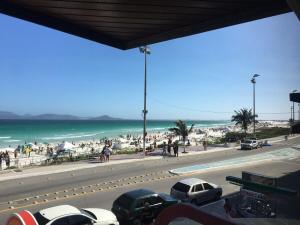 vistas a una playa con coches aparcados en la carretera en Frente mar praia do forte - Cabo Frio, en Cabo Frío