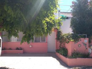a pink house with a white door and a tree at AMANECERES LAS GRUTAS II in Las Grutas