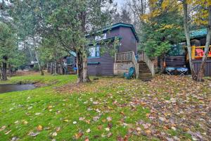 ein Haus mit einem Baum und Blätter auf dem Hof in der Unterkunft Pet-Friendly Adirondack Cabin with On-Site Lake in Saranac Lake