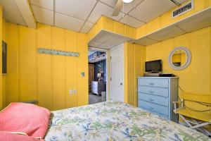 a bedroom with yellow walls and a bed and a tv at Peaceful Cottage By The Sea Oceanfront Home! in Surf City