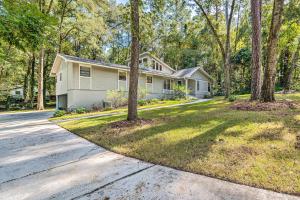 a white house with trees in front of a street at Remodeled Family Home with Patio - Walk to UF! in Gainesville