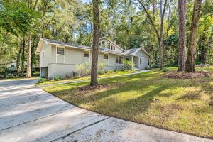 a white house with trees in front of a street at Walk to UF Remodeled Family Home with Patio! in Gainesville
