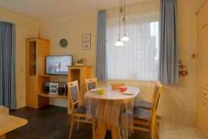 een woonkamer met een tafel en stoelen en een televisie bij KD12 48 Kajediek in Dorum Neufeld