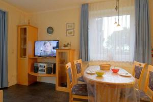 een woonkamer met een tafel en een televisie bij KD12 48 Kajediek in Dorum Neufeld