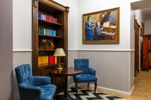 a room with a table and two blue chairs and a painting at Chopin Hotel in Lviv