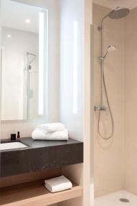 ein Bad mit einem Waschbecken und einer Dusche mit einem Spiegel in der Unterkunft Residhome Luxembourg Esch-Belval in Esch-sur-Alzette