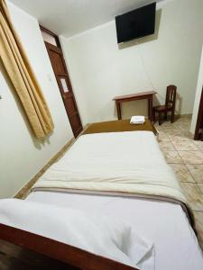 a bedroom with a bed and a desk and a television at Hostal El Gran Gocta in Chachapoyas