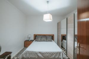 a white bedroom with a bed and a pendant light at Casinha do Roxo in Ervidel