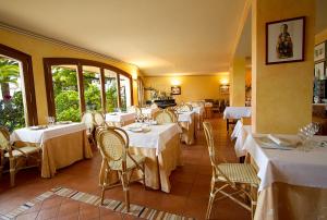 un restaurant avec des tables blanches, des chaises et des fenêtres dans l'établissement Hotel Antiga, à Calafell
