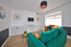 een woonkamer met een groene bank en een tv bij Air Host and Stay - Thomson House - Sleeps 4 2 mins walk from Stockport train station and town centre in Stockport