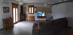 a living room with a couch and a tv at Casa Rural cerca de Morella in Zorita del Maestrazgo