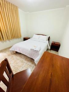 a bedroom with a white bed and a wooden table at Hostal El Gran Gocta in Chachapoyas