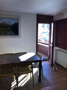 una sala da pranzo con tavolo, sedie e finestra di Appartamento Cervinia Cielo Alto direttamente sulle piste a Breuil-Cervinia